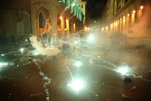 Anti-government protesters throw firecrackers against the riot police, background, in downtown Beirut, Lebanon, on Sunday.