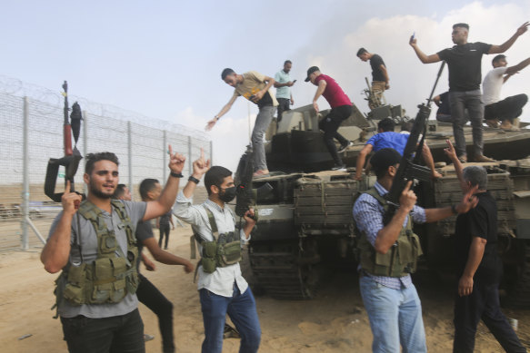 Militants celebrate by an Israeli tank at the border fence of the Gaza Strip on October 7.