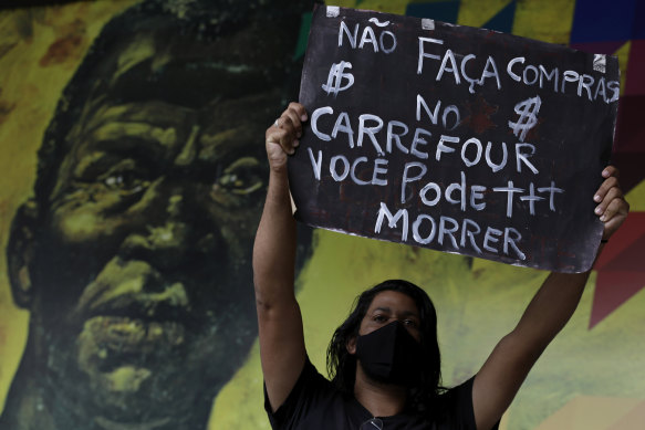 A protester holds up the Portuguese message "Don't shop at Carrefour, you could die", in front of an image of Brazilian runaway slave hero Zumbi dos Palmares during a protest over the killing of black man João Alberto Silveira Freitas at a Carrefour supermarket.