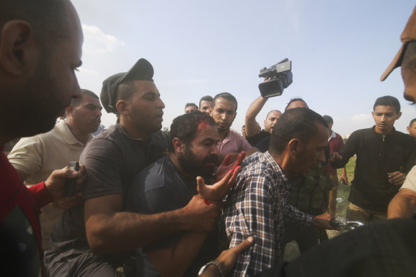 Palestinians transport a captured Israeli civilian (centre) from Kfar Azza kibbutz into the Gaza Strip on Saturday, 7 0ctober, 2023