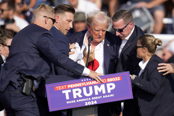 Donald Trump is helped off the stage following the shooting at his campaign rally.