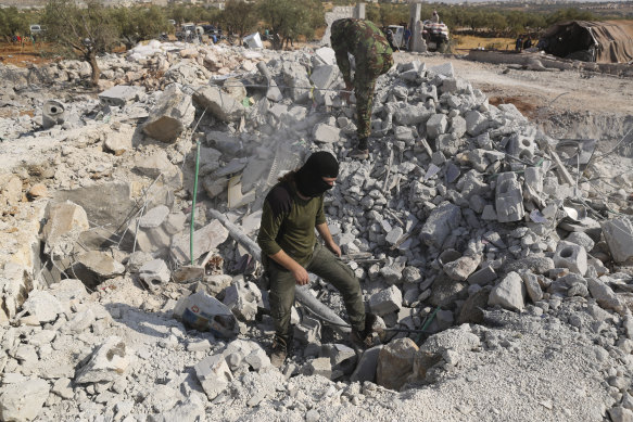 People look at a destroyed houses near the village of Barisha, in Idlib province, Syria.