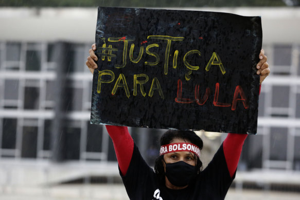 A demonstrator with a headband that reads “Bolsonaro out” raises a sign that reads “Justice for  Lula” in Brasilia on Monday.