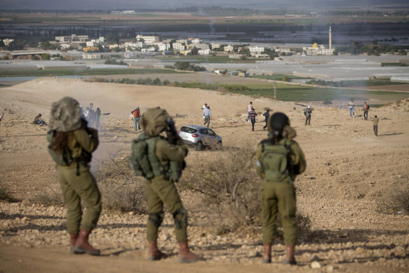 Palestinians and Israeli activists run away from tear gas fired by Israeli soldiers during a 2016 demonstration against the construction of Jewish settlements in the Jordan Valley.