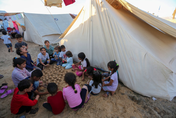 A group of children make sand castles beside tents at a refugee camp set up for Palestinians in Gaza.