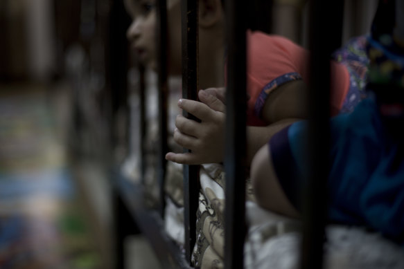 A child peeks out from her cot at Salhiya Orphanage for the children of Islamic State militants.