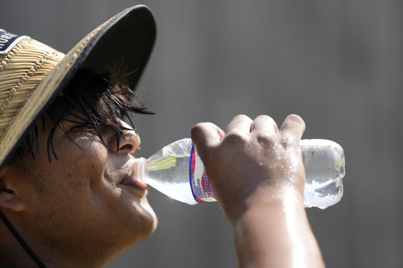 Carlos Rodriguez drinks water while taking a break from digging fence post holes in Houston..