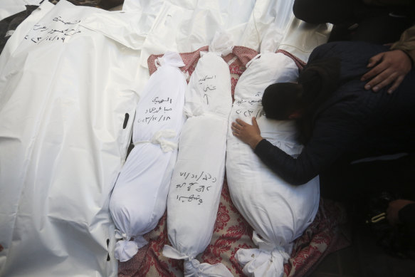 Palestinians mourn relatives killed in the Israeli bombardment of the Gaza Strip outside a morgue in Rafah, on Tuesday. The victims details are written on each wrapped body.