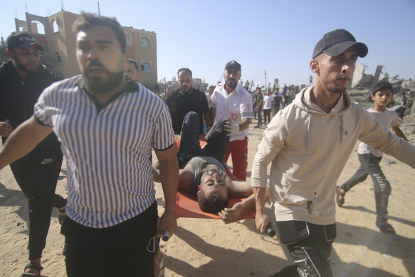 Palestinians carry a wounded man from the rubble of a destroyed building following an Israeli airstrike in Rafah, Gaza Strip on Friday (Gaza time).