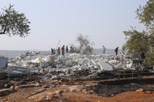 People look at a destroyed houses near the village of Barisha, in Idlib province, Syria.