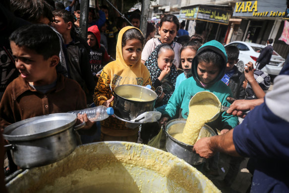 Displaced Palestinians receive cooked food rations in Deir-al-Balah in the central Gaza strip.
