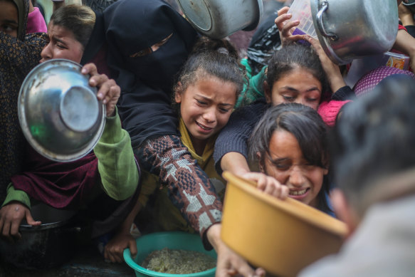 Citizens queue for food that is cooked in large pots and distributed for free in Rafah.