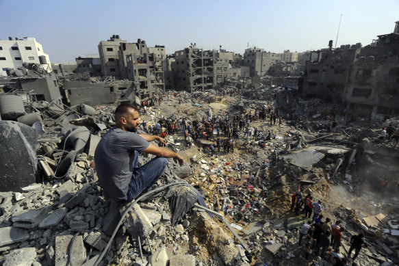 A man sits on the rubble overlooking the debris of buildings that were targeted by Israeli airstrikes in the Jabaliya refugee camp, northern Gaza Strip.
