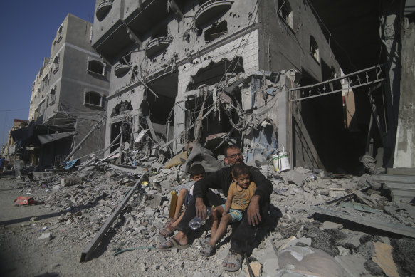 Palestinians sit outside their house following Israeli airstrikes in Rafah refugee camp, southern Gaza Strip, on Thursday.