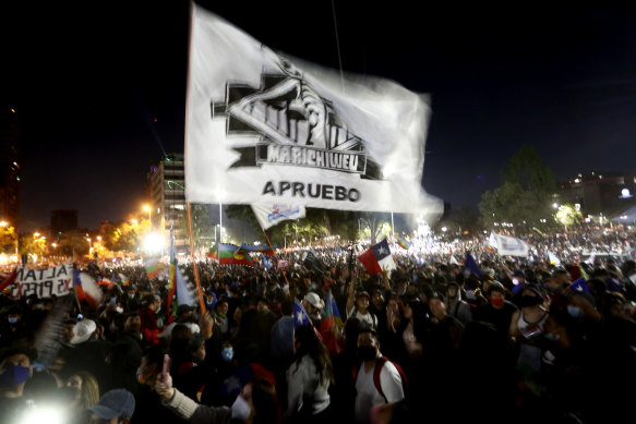 People hold a flag that reads "Approval" during a celebration as they wait for the official results of the referendum for a new constitution in Santiago on Sunday.