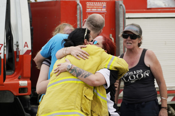 People are seen embracing at Numeralla Rural Fire Brigade near the scene of a water tanker plane crash.