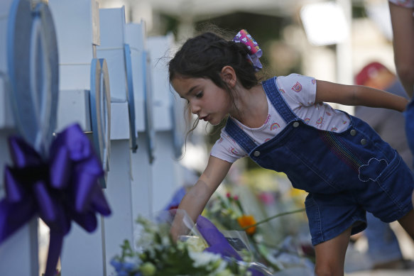 A child leaves flowers at a memorial site for the victims killed in this week’s elementary school shooting in Uvalde, Texas, Thursday, May 26, 2022.