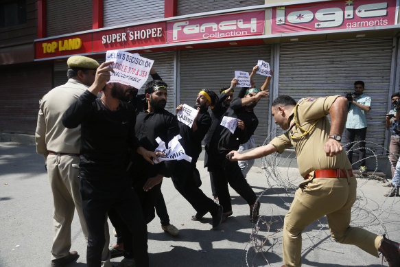 An Indian police officer charges at Kashmiri Shiite Muslims as they attempt to take out a religious procession.