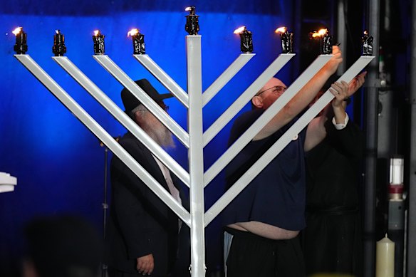 The father of 10-year-old Matilda, who died in the Bondi shootings,  lights a candle on a menorah.