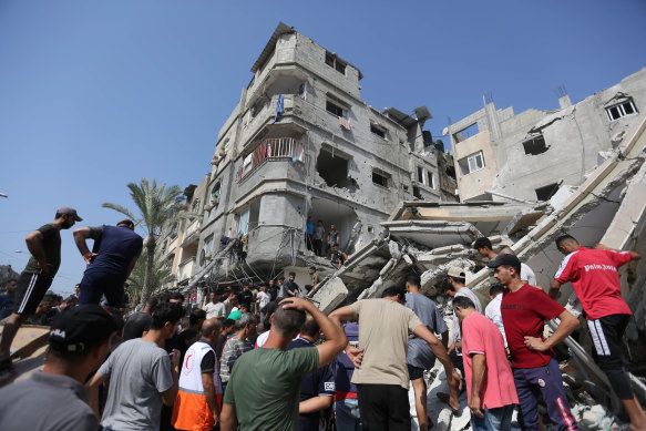 Palestinian emergency services and local citizens search for victims in buildings destroyed during Israeli air raids.