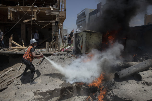 A Palestinian firefighter extinguishes a fire at a beachside cafe in Gaza City after it was hit by an Israeli air strike.