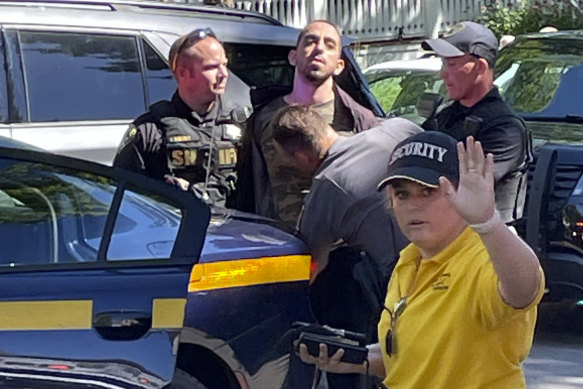 Law enforcement officers detain Hadi Matar (centre) following the stabbing of Salman Rushdie.