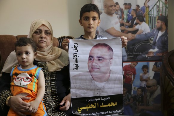 Amro el-Halabi holds a picture of his father, Mohammed, who was the Gaza director of the international charity World Vision, now found guilty of diverting sums to Hamas.