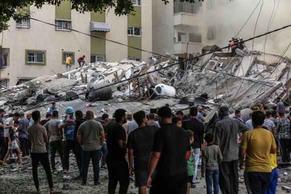 Palestinians inspect a destroyed building as emergency responders try to contain fires after Israeli jets bombed Gaza City in the Gaza Strip.