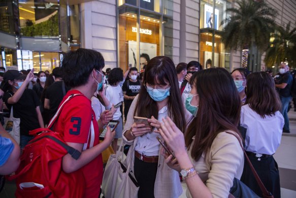 Pro-democracy protesters check their phones for a 6pm "big announcement" from protest leaders on October 20 in Bangkok.