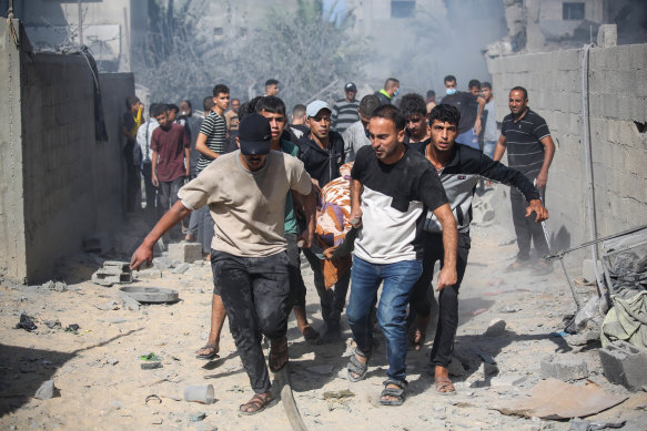 Palestinian emergency services and citizens carry a victim of an Israeli air strike in Khan Yunis, in the southern Gaza Strip, on October 18.