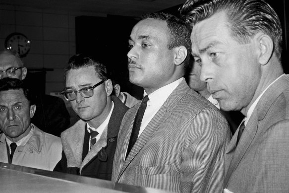 Thomas 15X Johnson, centre, is booked as the third suspect in the slaying of Malcolm X, in New York, March 3, 1965.