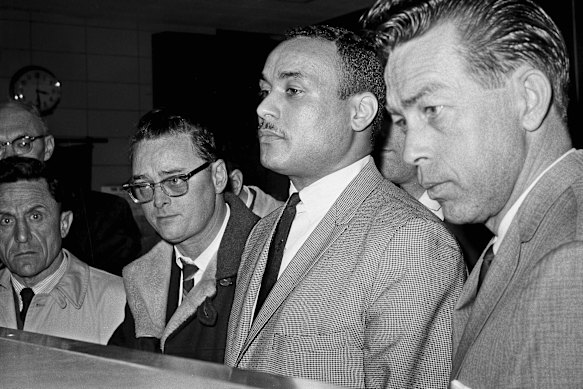 Thomas 15X Johnson, centre, is booked as the third suspect in the slaying of Malcolm X, in New York, March 3, 1965.