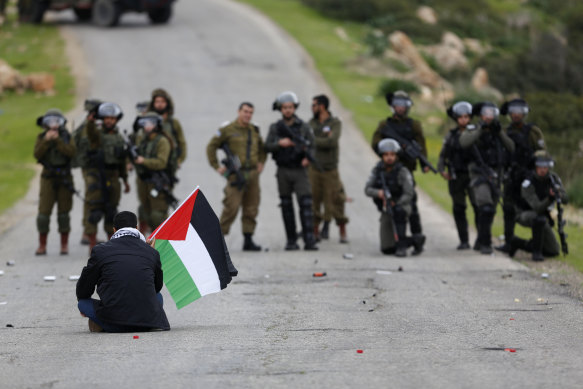 A Palestinian demonstrator sits in front of Israeli occupation troops during protests in the Jordan Valley in February.