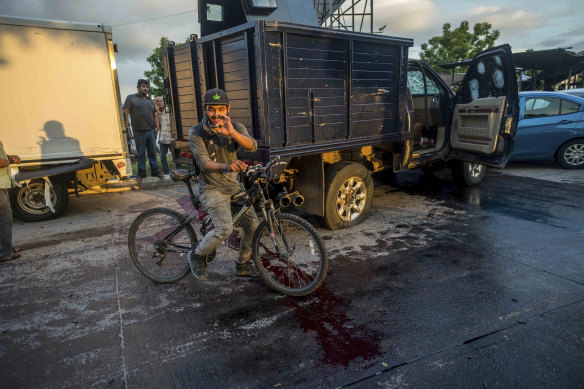 A man handles a bullet cartridge on a bloodied street.