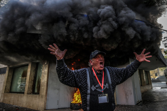 A bank client chants slogans as  he protests in front of a local bank branch whose entrance was set on fire in Beirut., Lebanon, on Thursday.