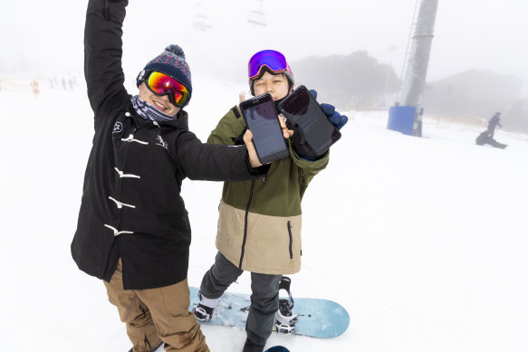 Jianfeng Ruan (left) and Zi Tao from Melbourne display their negative COVID-19 test text message as they enjoy their first runs of the season at Mount Buller.