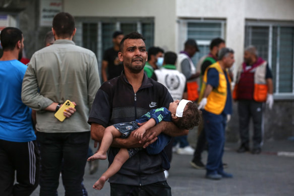 A man carries an injured child outside the Al-Shifa Hospital following Israeli airstrikes on Gaza City on Tuesday.