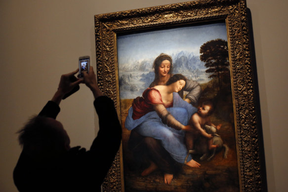 A journalist takes a snapshot of the "The Virgin and Child with Saint Anne".