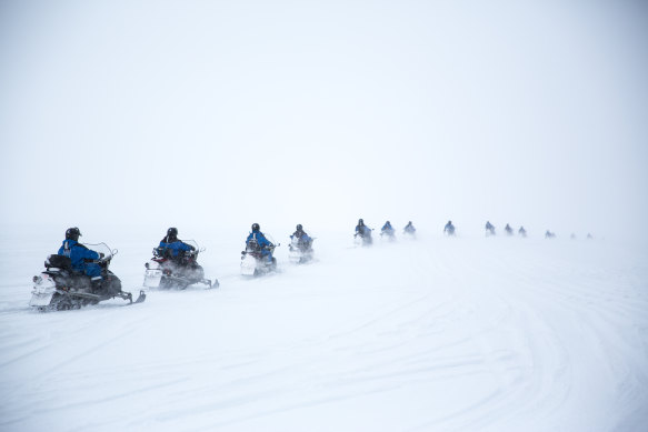 A line of snowmobiles head out into the wilderness.