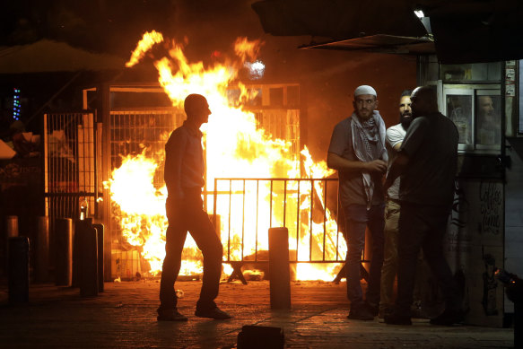 Palestinians gather near a fire burning next to the Damascus Gate to the Old City of Jerusalem during clashes between police and Palestinian protesters on Monday, May 10, 2021. 