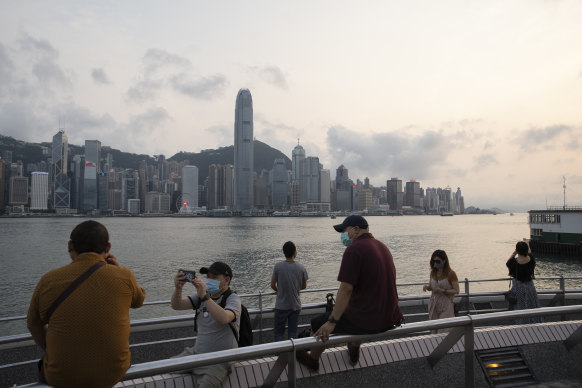 People wearing protective masks stand along the Tsim Sha Tsui waterfront in Hong Kong. 