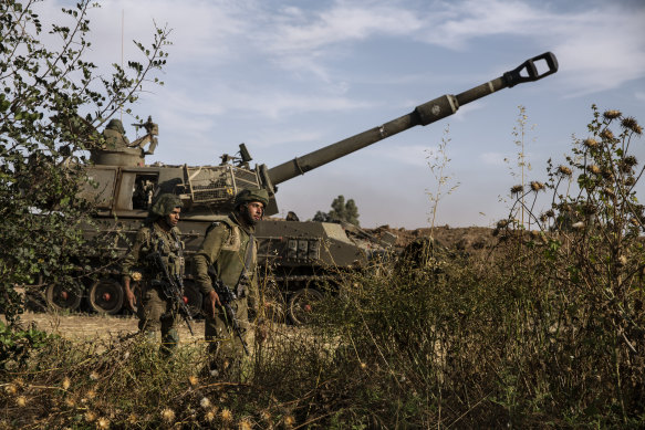 Two Israeli soldiers walk around an artillery unit, at the Israeli Gaza border, on Sunday.