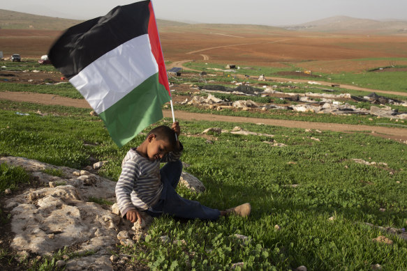 A boy holds a Palestinian flag after Israeli troops demolished tents and other structures of the Khirbet Humsu hamlet in the Jordan Valley in the West Bank on Wednesday.