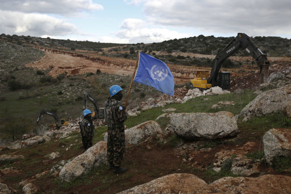 UN peacekeepers hold their flag, as they observe Israeli excavators attempt to destroy tunnels built by Hezbollah near the border in 2019.