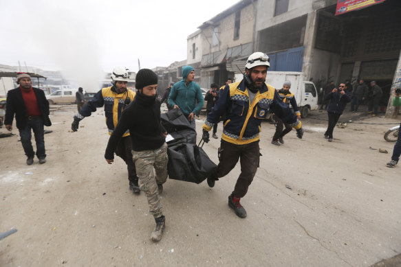 Emergency services carry the body of a person killed in a government air strike in the city of Idlib  on February 11.