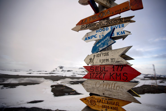 Wooden arrows show the distances to various cities on King George Island, Antarctica.