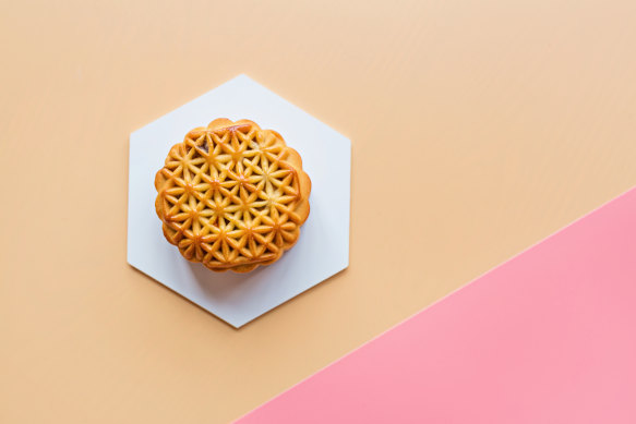 A traditional mooncake decorated with an intricate pastry pattern.