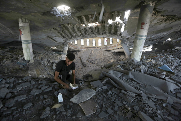 A man looks at damaged books inside a mosque destroyed in an Israeli air strike in Khan Younis, Gaza Strip. 