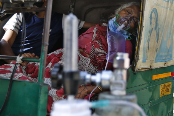 A coronavirus patient wearing an oxygen mask waits inside an auto rickshaw to be admitted to a dedicated COVID-19 government hospital in Ahmedabad, India, on Saturday.