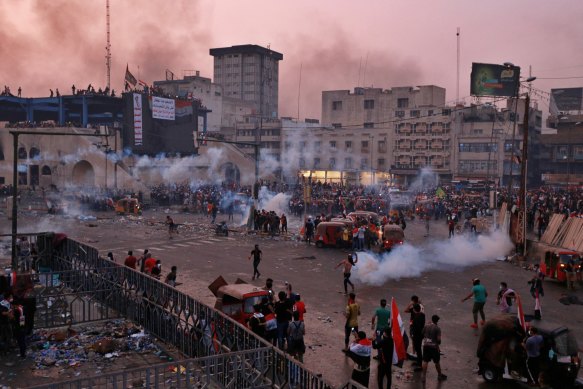 Anti-government protesters gather while Iraqi forces fire tear gas during a demonstration in Tahrir Square in Baghdad on Monday.